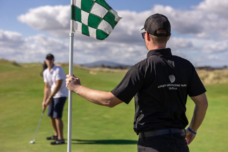 LGST host holding the flag as a golfer lines up a putt at Barnbougle