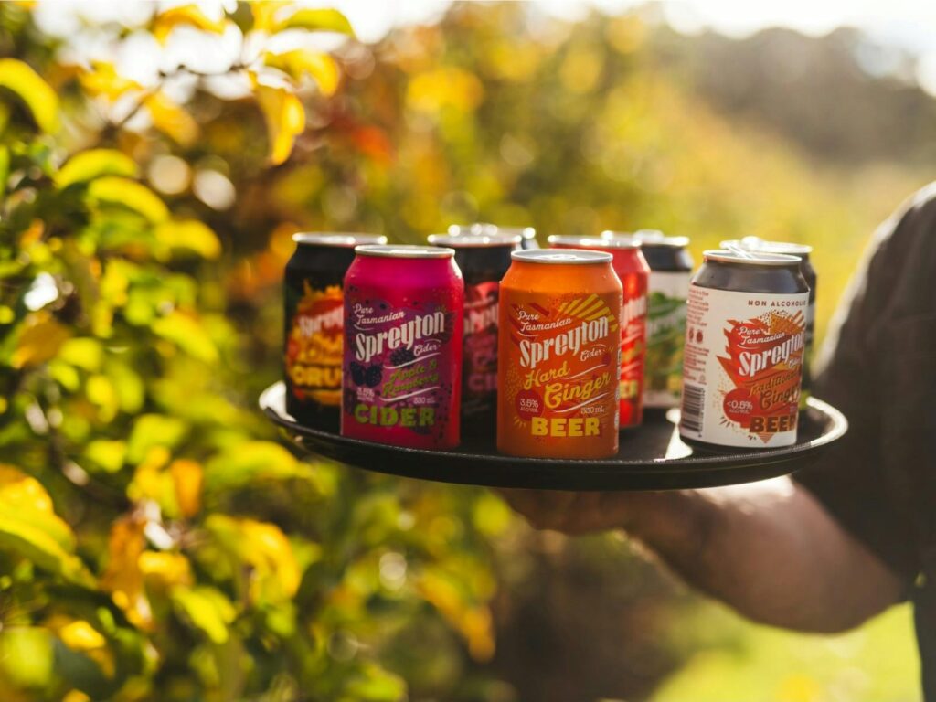 Selection of Spreyton Cider cans displayed on a tray outdoors.